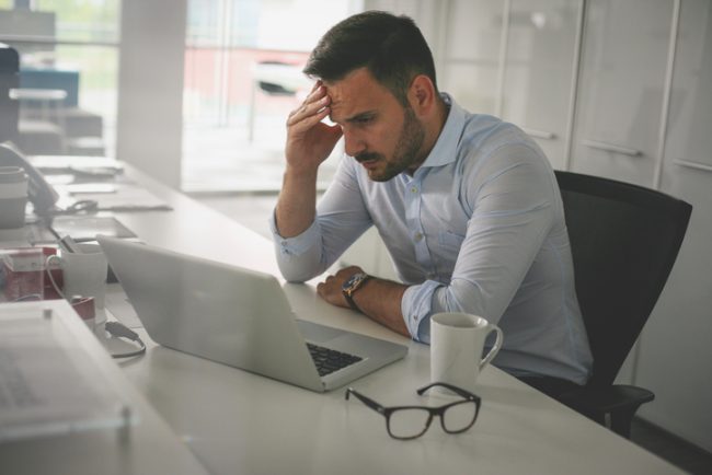Homem preocupado sentado em frente ao seu computador Homem preocupado sentado em frente ao seu computador